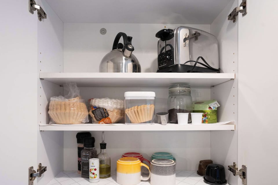 Well-stocked kitchen cabinets with cookware, spices, coffee filters, kettle, and toaster. Everything you need for your morning routine.
