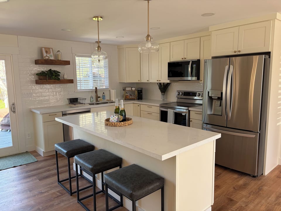Fully stocked kitchen with 3 bar stools for seating.