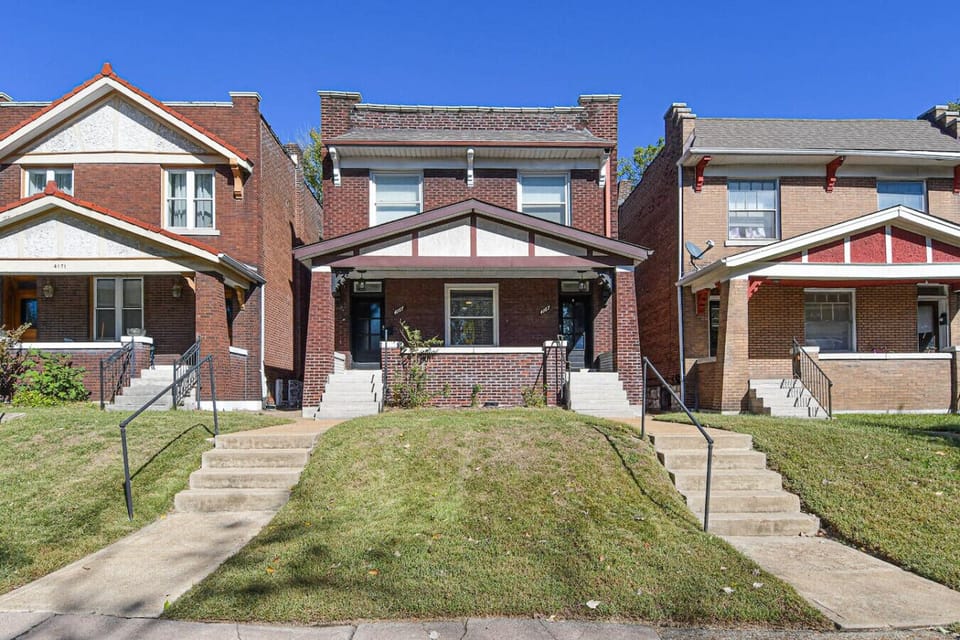 Charming Exterior: Relax on the steps of this inviting brick home in vibrant St. Louis!