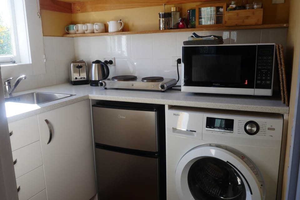 Kitchen includes small fridge, microwave, toaster, jug and Washing machine

