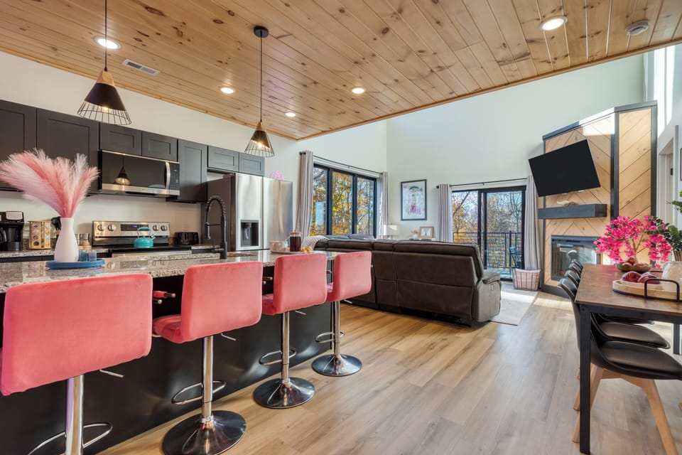 Bright, modern open-concept living with stylish pops of color and forest views.