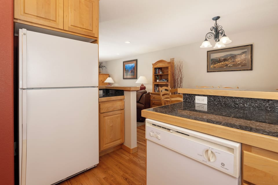 Prepare delicious meals in your fully equipped kitchen with granite countertops, white appliances, and warm wood cabinets.