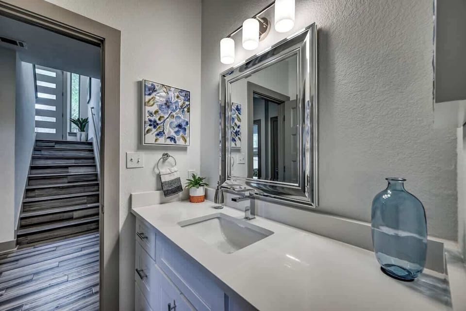 Modern vanity bathroom with framed mirror and colorful artwork.