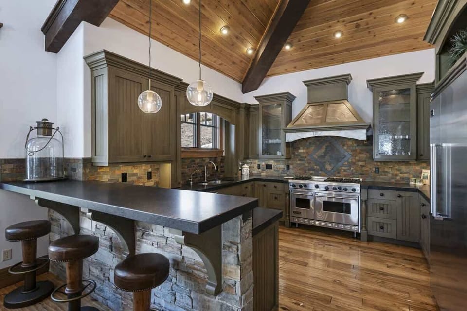 Rustic-modern kitchen with wood ceilings, stone accents, and high-end appliances.
