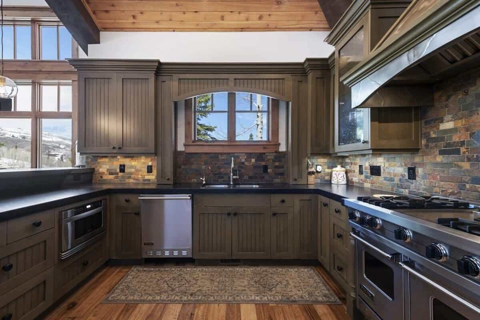 Rustic kitchen with wood cabinetry and scenic views.