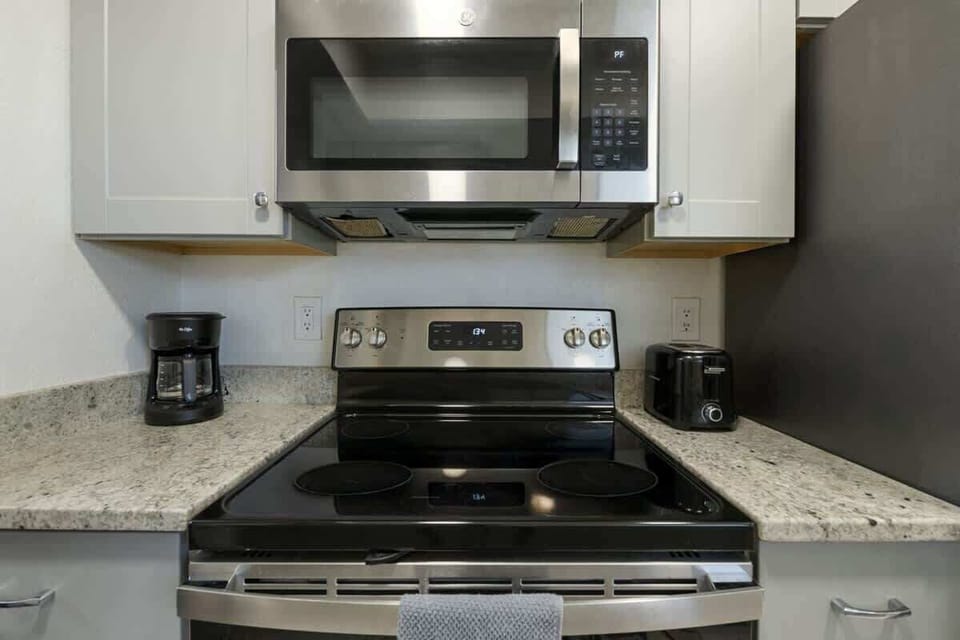 Modern kitchen setup featuring stainless steel appliances, granite countertops, and essentials like a coffee maker and toaster — perfect for convenient cooking.