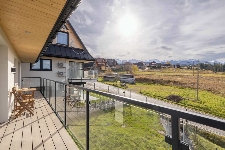 A balcony with a view of nearby houses and mountain greenery. Ideal for relaxing outdoors and admiring the scenery.