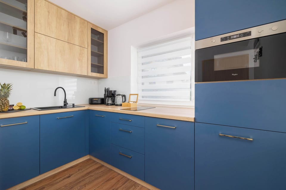A modern kitchen featuring deep blue cabinets and built-in appliances. The space is stylish and functional, ideal for preparing meals.