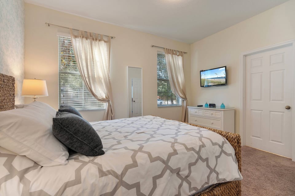 Awake to natural light streaming through large windows, illuminating the plush bedding and elegant patterns. The tasteful decor and soothing color palette create a cozy atmosphere, making this bedroom a perfect tranquil retreat.