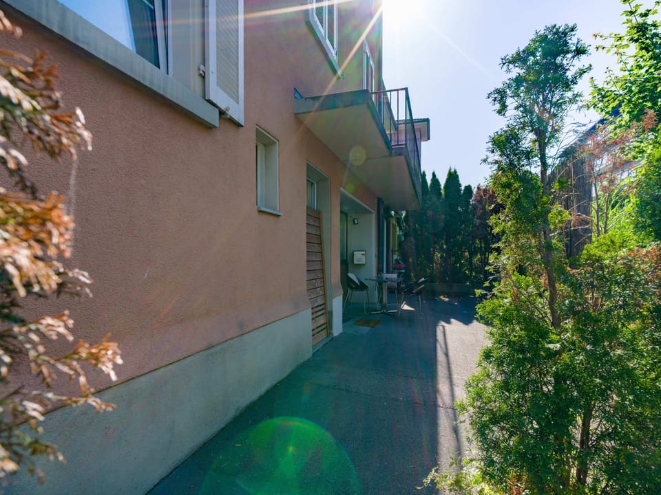 Quiet pathway leading to the guest rooms, surrounded by greenery and a relaxed residential setting.
