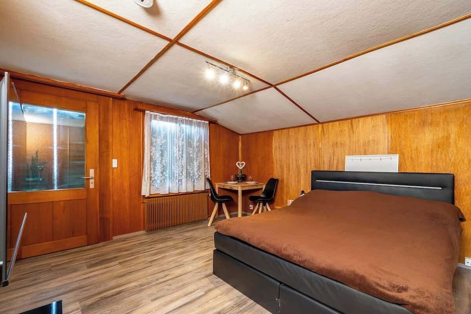 Bright bedroom area with large box-spring bed and warm wooden interior
