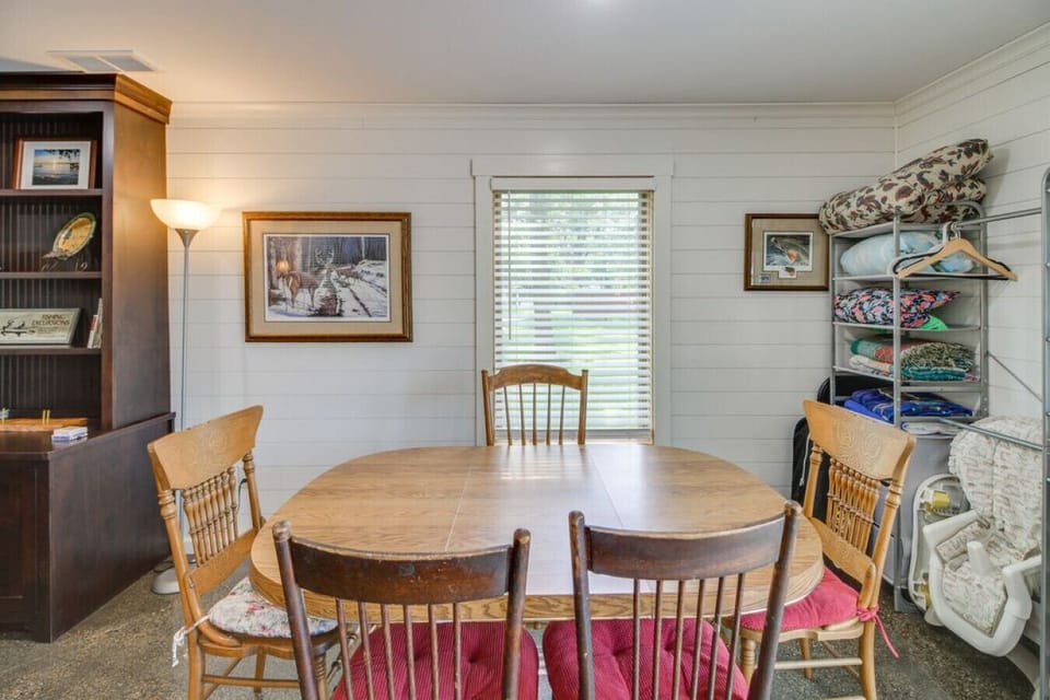 Second dining space | Round wooden table with mixed chairs, shiplap walls, bookshelf, and open shelving for storage