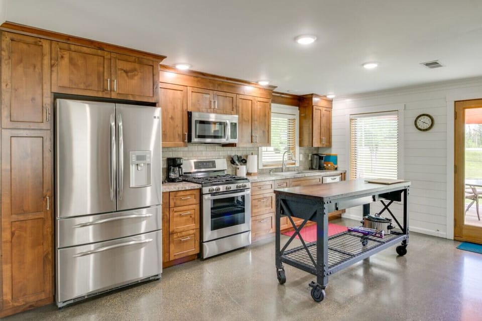 Modern kitchen | Stainless steel appliances, wood cabinetry, center island, and patio access
