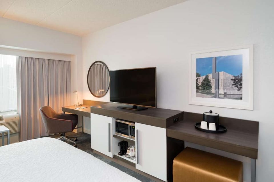 Bedroom with TV, desk, framed art, and gray curtains