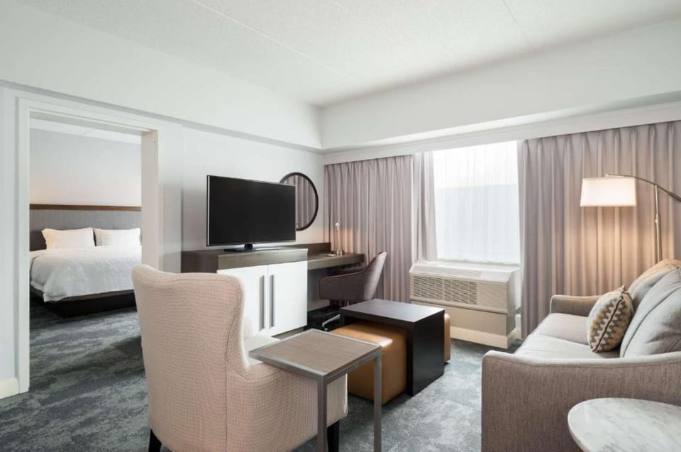 Living space with TV, sofa, desk, and soft window curtains