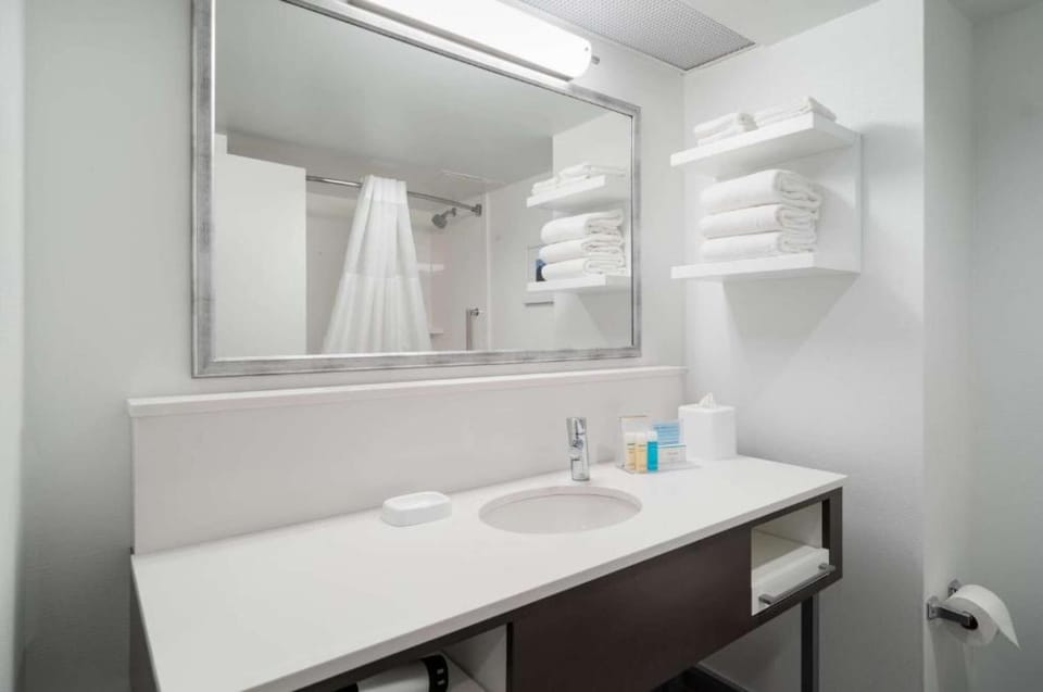 Bathroom with sink, mirror, and shelves filled with white towels