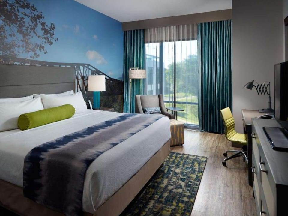 King bed room with bright window, desk, and green chair