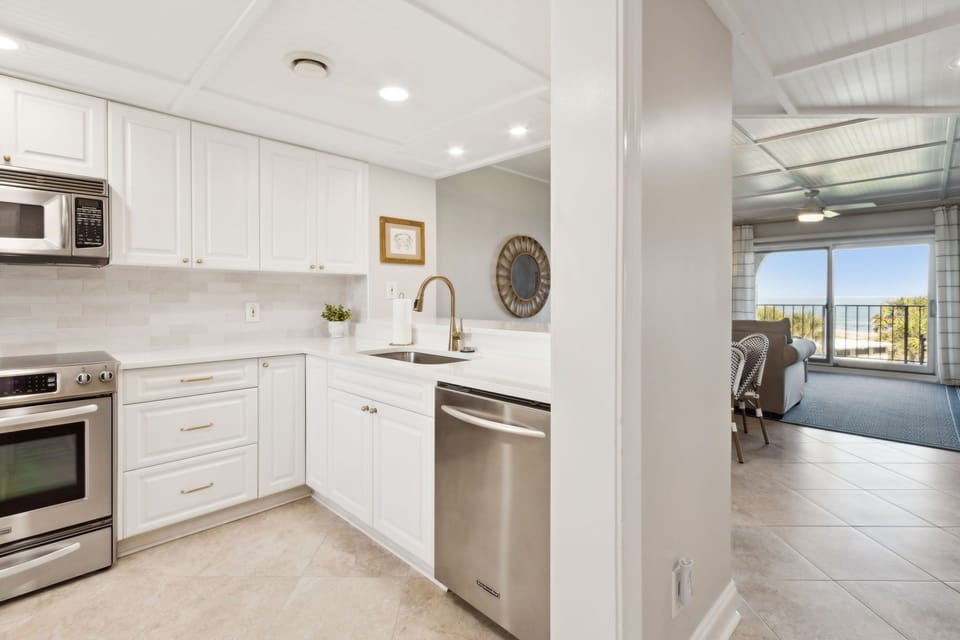 Luxury Remodeled Kitchen with Stainless Steel Appliances, Stunning White Cabinetry, Quartz Countertops, Gold Finishes and a Trendy Backsplash
