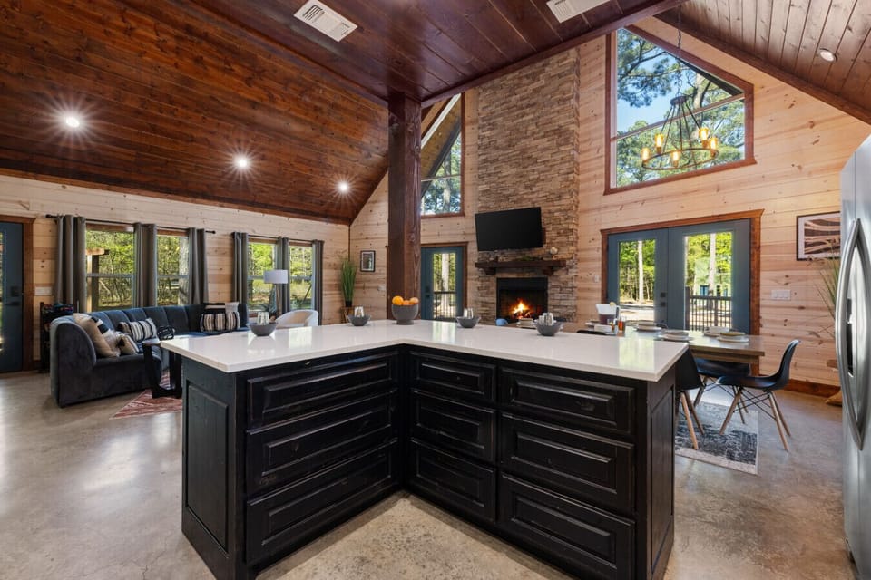 Spacious kitchen and living area with floor-to-ceiling windows, cozy fireplace, and multiple seating zones designed for family game nights, movie marathons, and relaxed retreats in Broken Bow