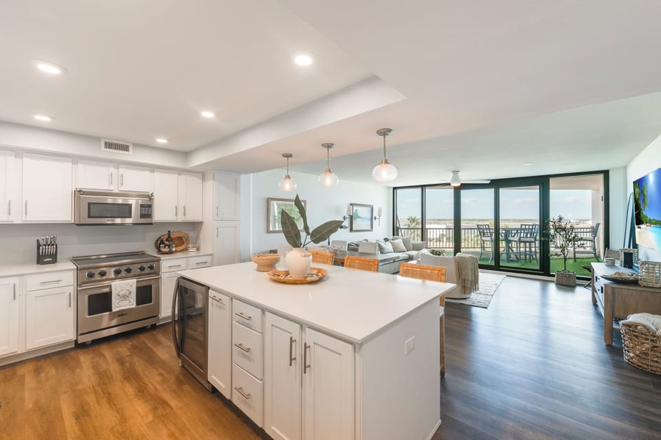 Your modern open-concept kitchen flows seamlessly into the living area, where floor-to-ceiling windows flood the space with natural light and frame stunning balcony views.