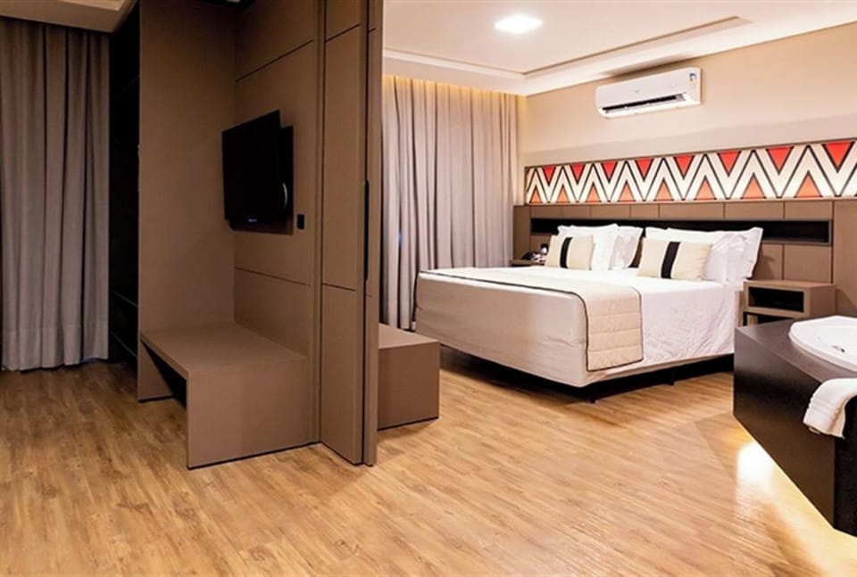 Stretch out in a stylish suite bedroom with warm ambient lighting.