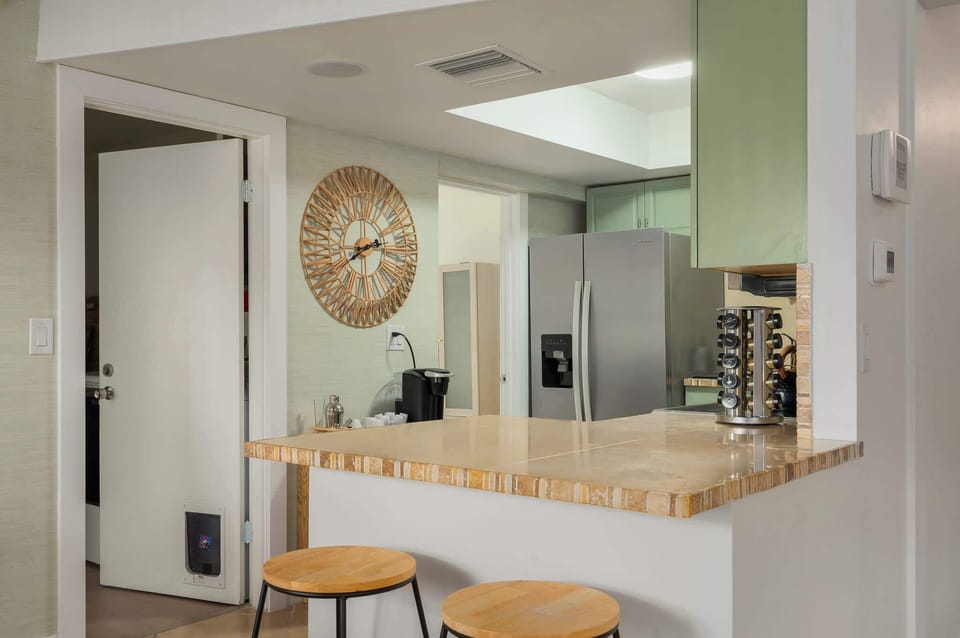 Bright, open kitchen bar with natural wood counters, modern appliances, and casual seating. Perfect for quick breakfasts, evening drinks, or chatting while meals are prepared in this inviting, beachy space.