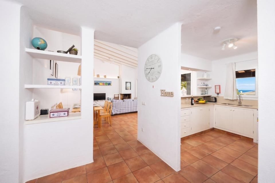 Open-plan living room with sofas, dining area, kitchen, ornamental fireplace, A/C, WiFi internet, and satellite TV