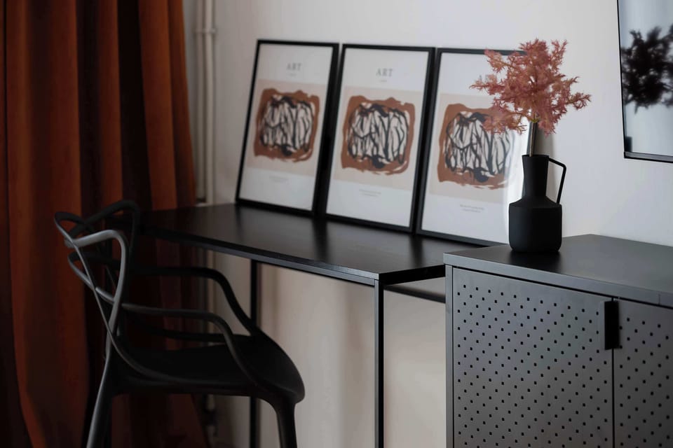 A small black desk with framed photos and a vase for decoration. The minimalist style enhances elegance.