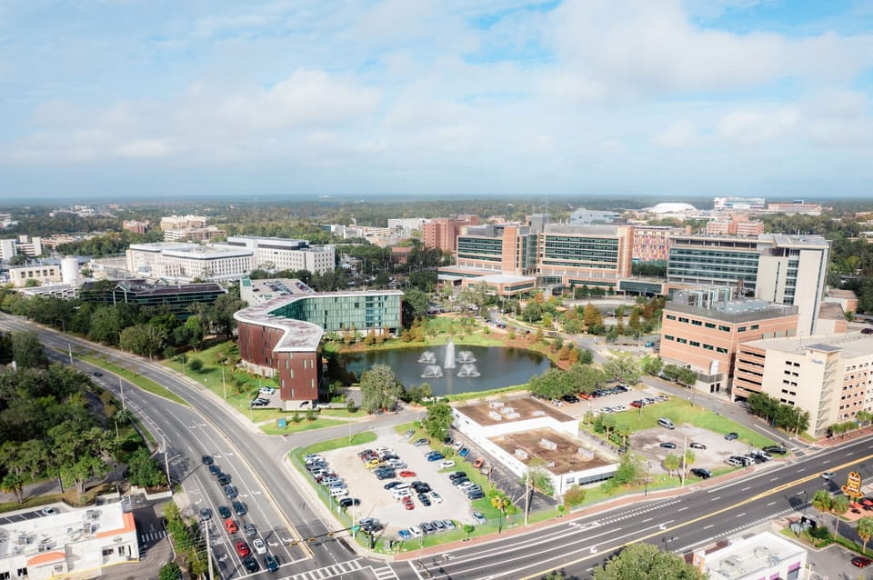 An aerial view showcases the modern architecture of Hotel ELEO amidst the vibrant landscape of the University of Florida campus.