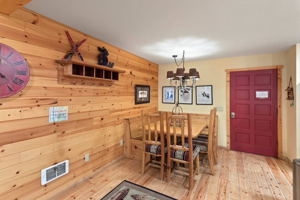 Rustic pine dining bench seats 8 under a charming pinecone chandelier.