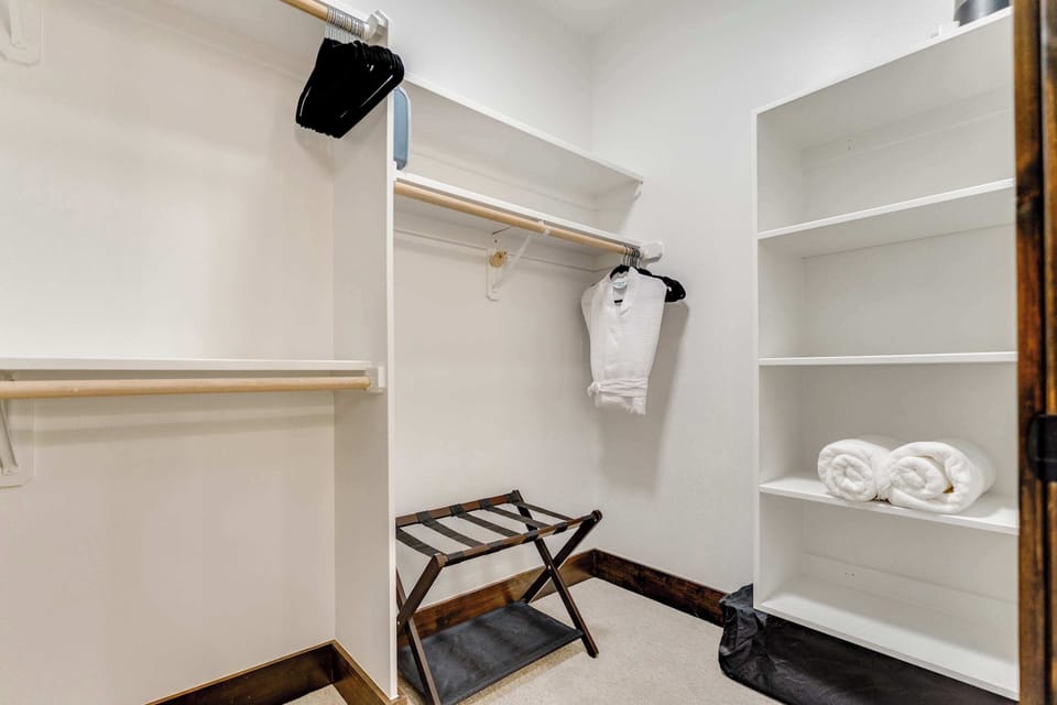 Large primary walk-in closet with hangers, luggage rack, shelves, and plenty of space to spread out.