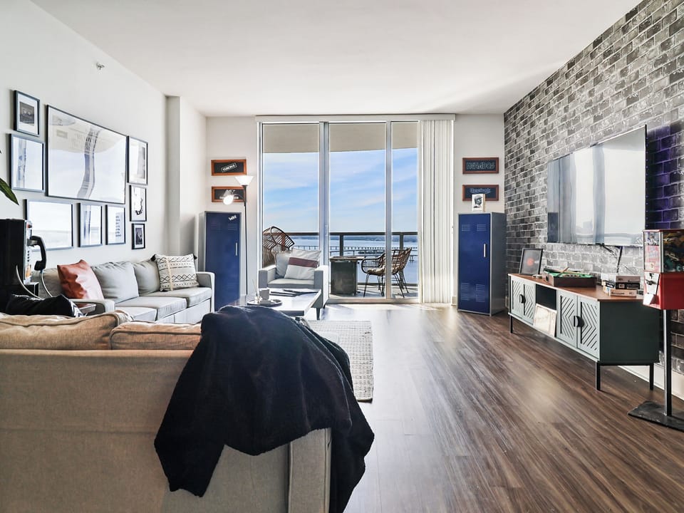 Spacious open concept living area, exposed brick-style wall, and balcony access.