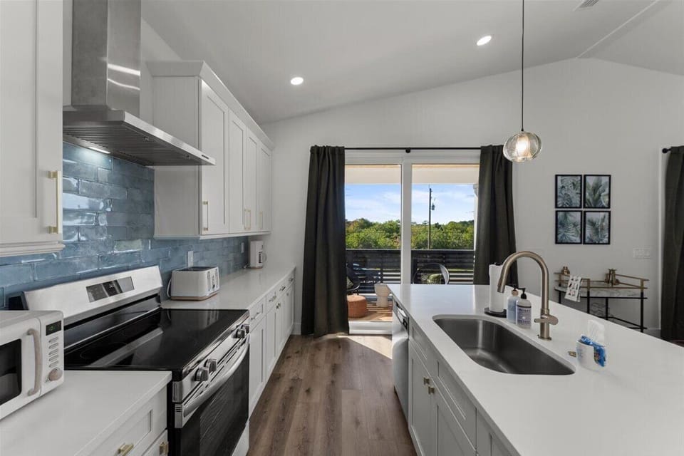 Fully equipped kitchen with stainless steel appliances, quartz countertops, and access to the outdoor balcony.