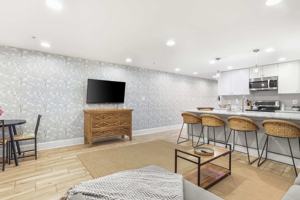 View of fully equipped kitchen, kitchen counter with bar stools, wall mounted TV