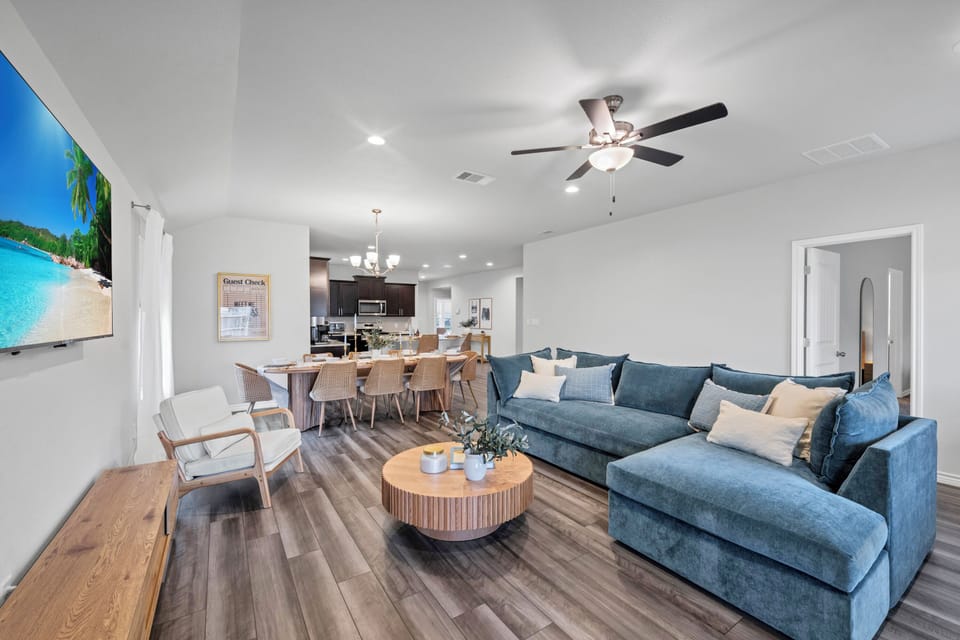 This spacious and inviting living room offers a comfortable place to relax, featuring cozy seating, modern décor, and an open layout that connects seamlessly to the kitchen and dining area—perfect for families, groups, and long-term stays.