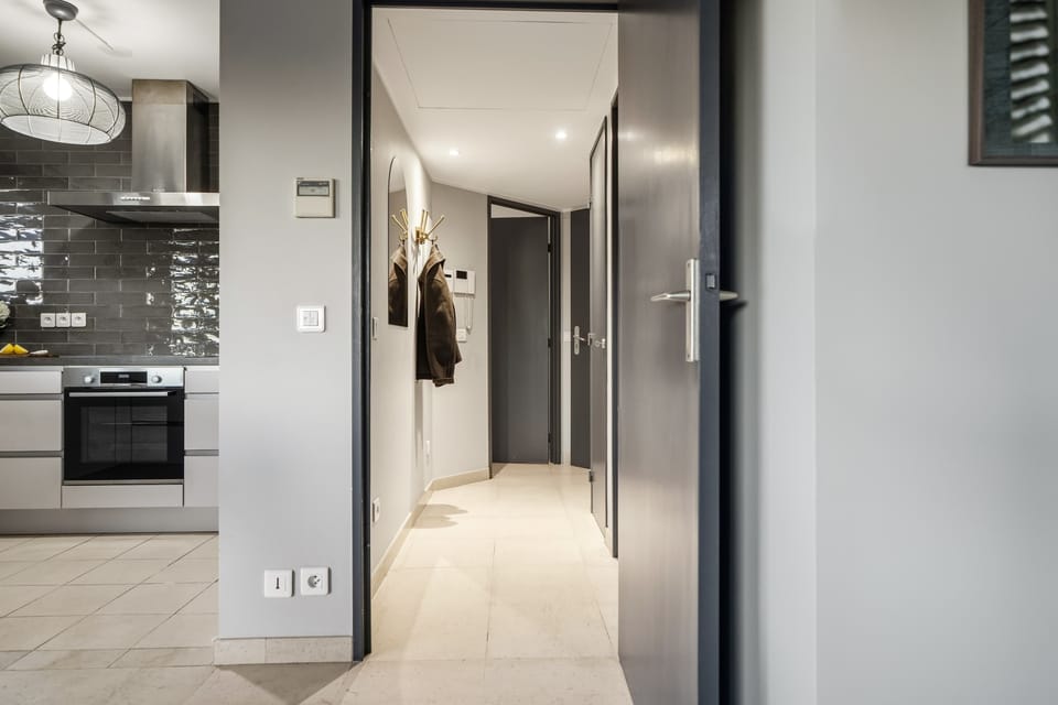 Clean, well-lit hallway connecting kitchen, living area, and private rooms — a functional layout for group travel or remote work stays.