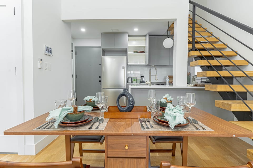 Open dining area and kitchen nook with modern table, art accents and adjacent balcony access.