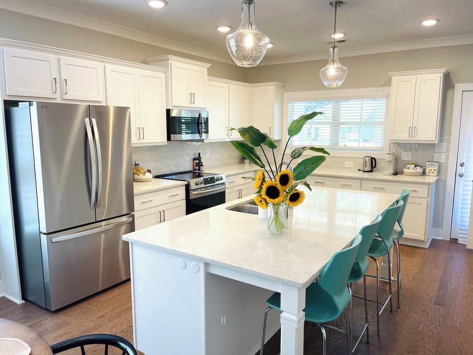 Fully equipped modern kitchen with large island, electric stove, and everything you need to cook, dine, and connect.