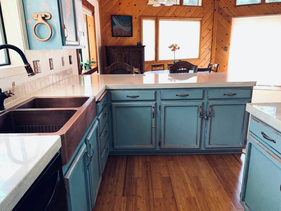 Our copper blue kitchen features hand-painted cabinets, crema marfil marble countertops, and a copper sink