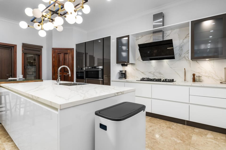 This gourmet kitchen is a masterpiece of design, featuring a huge marble-style island, sleek, high-gloss cabinetry, and premium appliances. From casual breakfast to a five-course dinner, you have everything you need to cook and entertain in luxury.
