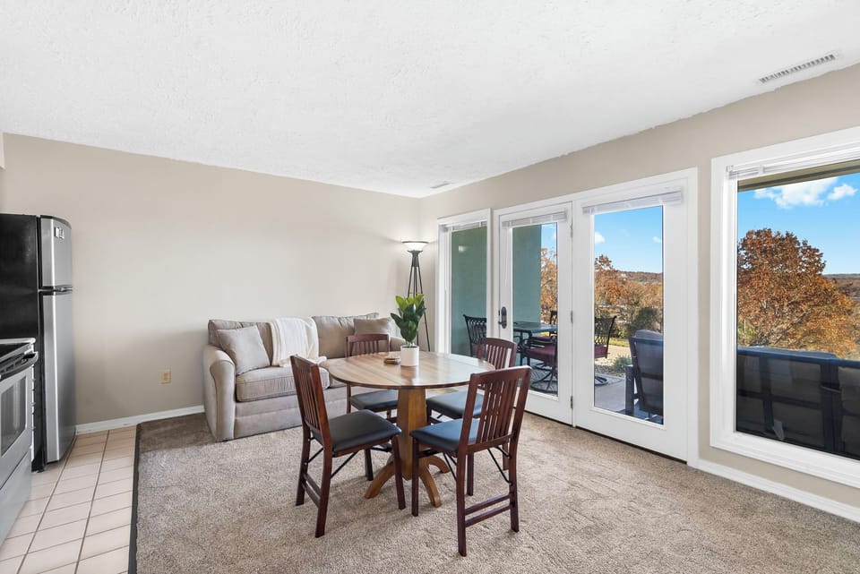The open floor plan features a fully equipped kitchen, a dining table, a living area with a sleeper sofa and patio access, a bedroom, and a bathroom.