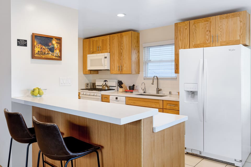 Bright and functional kitchen with a breakfast bar, modern appliances, and warm wood cabinetry.