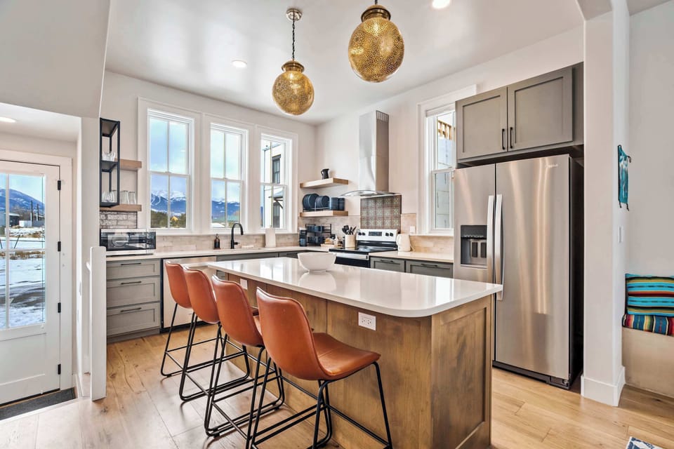 The kitchen features an oversized island with bar seating, warm wood cabinetry, and bright natural light. It’s a comfortable, functional space for cooking and gathering.