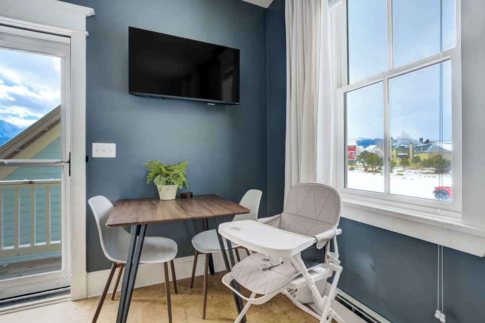The dining corner includes seating for two and a high chair for families traveling with little ones. Natural light and a mounted Smart TV make it a bright and convenient spot for meals or downtime.