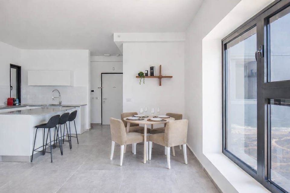 Dining table beside bright kitchen offers relaxed setting for meals before heading to nearby beach.