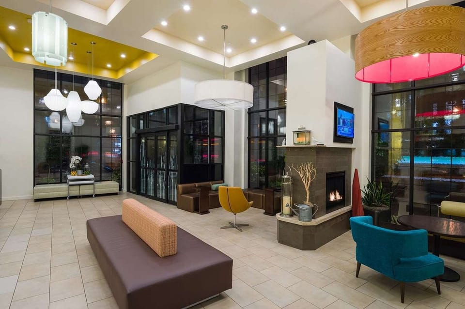 Bright lobby with comfy seats, tall windows, and warm fireplace