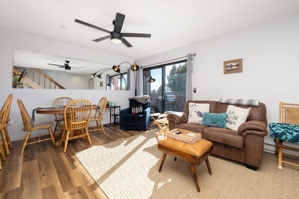 Relax in your bright, open living space with cozy seating, warm wood accents, and natural light streaming through large windows.