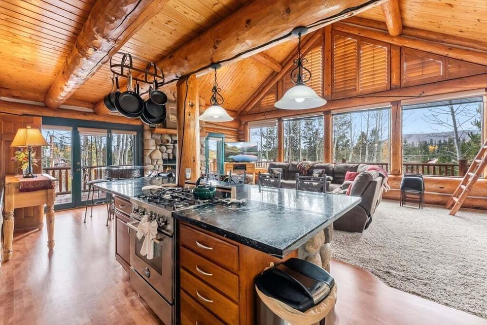 You'll love cooking in this stunning log cabin kitchen featuring granite counters, modern appliances, and breathtaking mountain views through expansive windows.