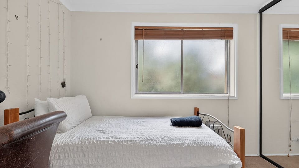 Bright bedroom with a double bed and large window.