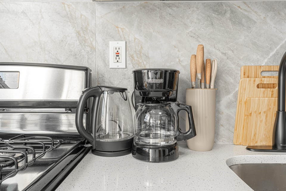Modern kitchen with black stove, kettle, coffee maker and knife sets
